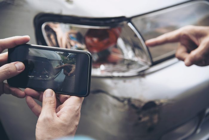 car insurance quotes image person taking photograph of damaged car